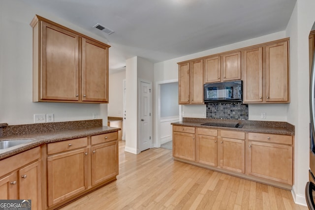 kitchen featuring light wood-type flooring, black appliances, backsplash, and sink