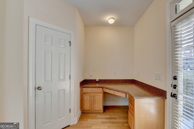 office with built in desk and light wood-type flooring