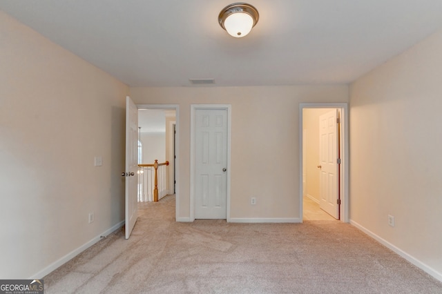 unfurnished bedroom with light carpet and a closet