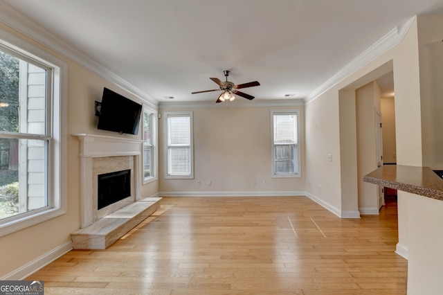 unfurnished living room featuring ceiling fan, a high end fireplace, and a healthy amount of sunlight