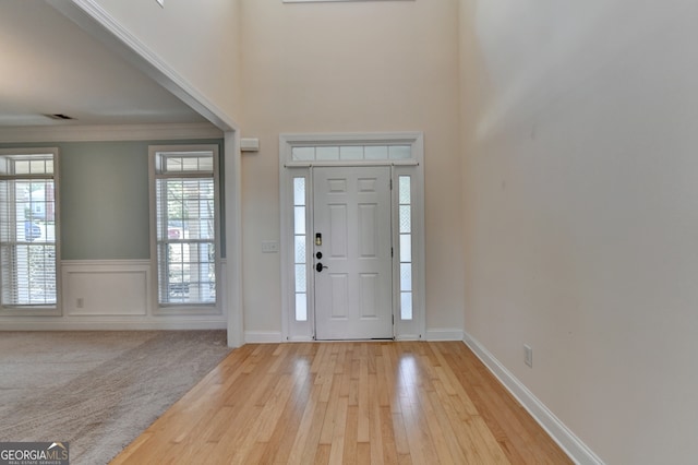 entrance foyer with ornamental molding and light hardwood / wood-style floors