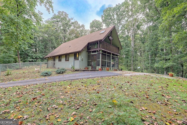 view of front of property featuring a sunroom, fence, and a forest view