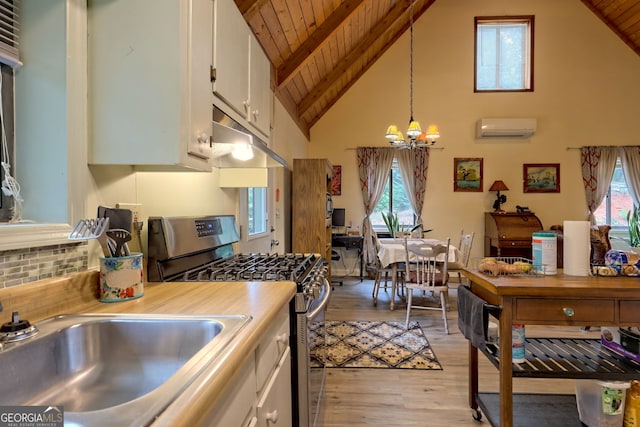 kitchen featuring wood ceiling, gas stove, white cabinetry, hanging light fixtures, and a wall mounted AC