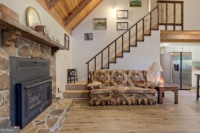 living room featuring light wood-type flooring, wood ceiling, a fireplace, and high vaulted ceiling