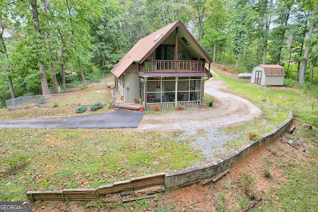 rear view of house with a sunroom and a storage unit