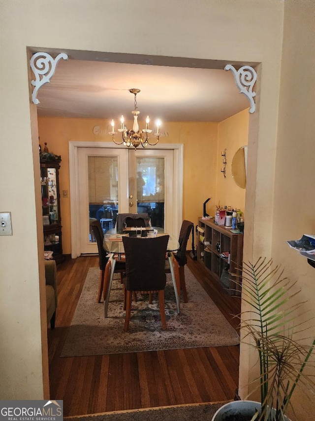 dining area featuring dark wood-type flooring and an inviting chandelier