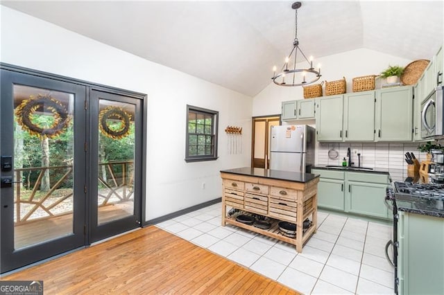 kitchen with dark countertops, lofted ceiling, light wood-style flooring, decorative backsplash, and appliances with stainless steel finishes