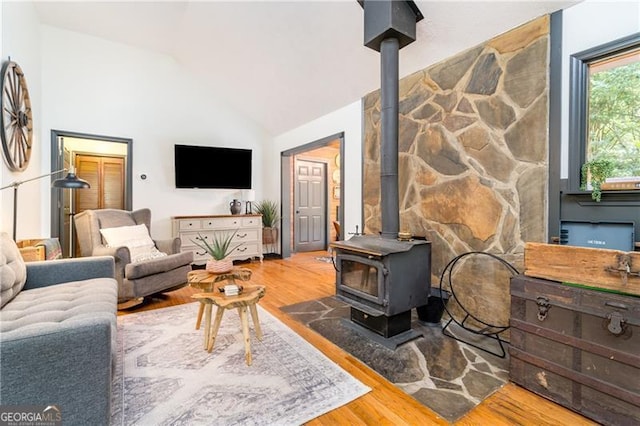 living area featuring vaulted ceiling, wood finished floors, and a wood stove