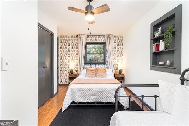 bedroom with light wood-style floors, ceiling fan, and wallpapered walls