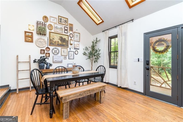 dining area with lofted ceiling with skylight, light wood-style flooring, and baseboards