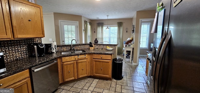 kitchen featuring sink, hanging light fixtures, decorative backsplash, appliances with stainless steel finishes, and dark stone countertops