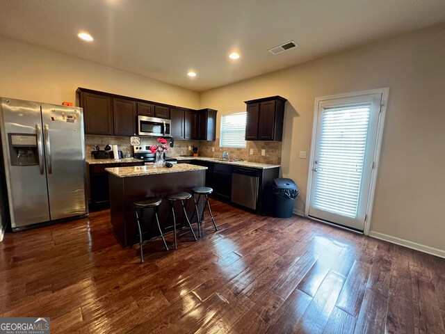 kitchen featuring sink, a kitchen island, backsplash, stainless steel appliances, and dark hardwood / wood-style floors