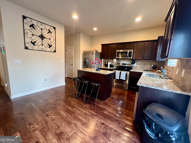 kitchen with a kitchen breakfast bar, a kitchen island, stainless steel appliances, dark hardwood / wood-style floors, and sink