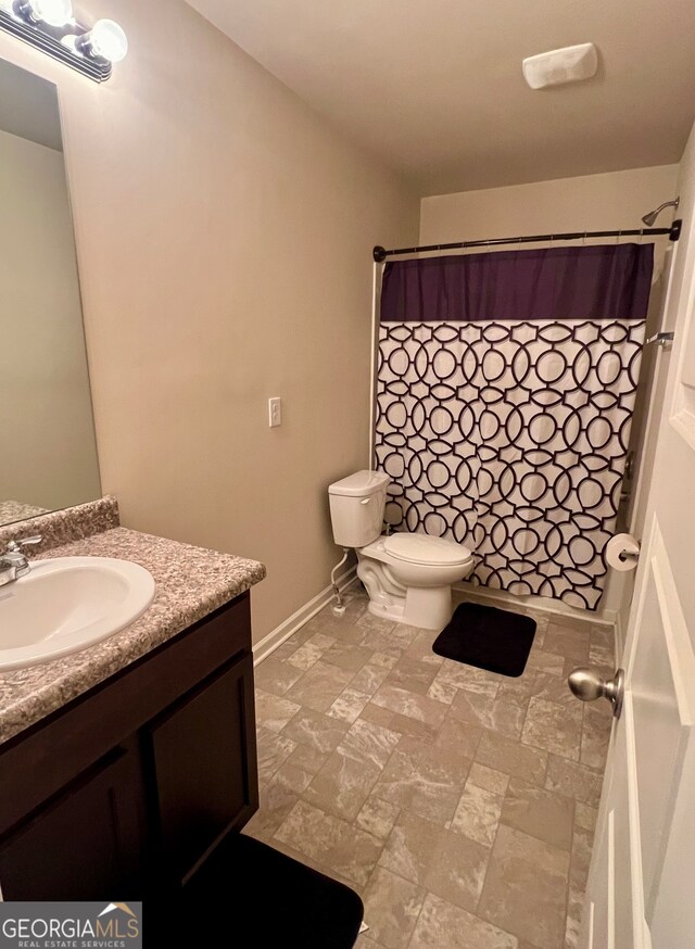 bathroom with curtained shower, vanity, and toilet