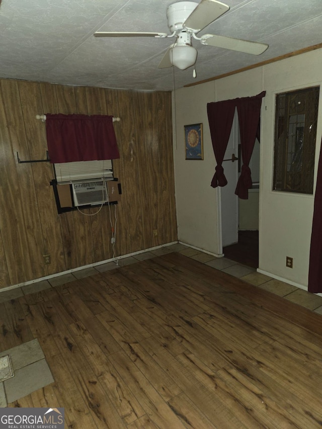 unfurnished room featuring ceiling fan, cooling unit, wooden walls, and hardwood / wood-style floors