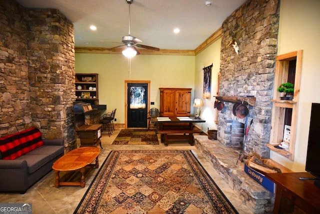 tiled living room featuring ceiling fan, a stone fireplace, and ornamental molding