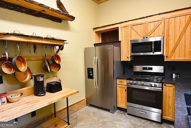 kitchen with appliances with stainless steel finishes, backsplash, and light tile patterned flooring