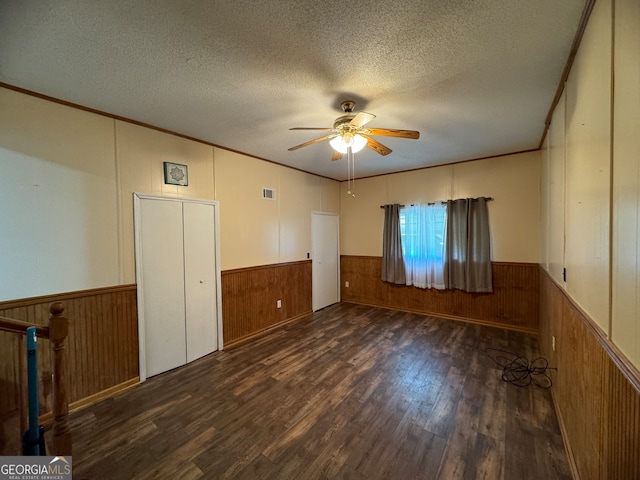 empty room featuring a textured ceiling, crown molding, dark hardwood / wood-style flooring, and ceiling fan