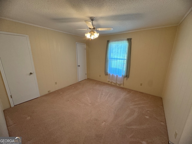 carpeted spare room featuring a textured ceiling, crown molding, and ceiling fan