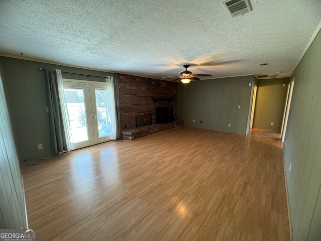 unfurnished living room featuring a brick fireplace, a textured ceiling, light hardwood / wood-style floors, and ceiling fan