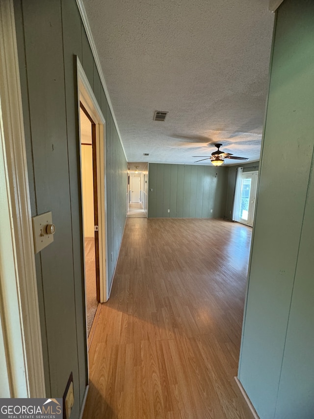 hallway with ornamental molding, light wood-type flooring, and a textured ceiling