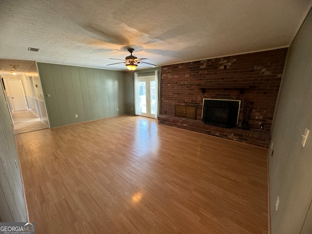 unfurnished living room featuring a textured ceiling, a fireplace, ceiling fan, and light hardwood / wood-style flooring