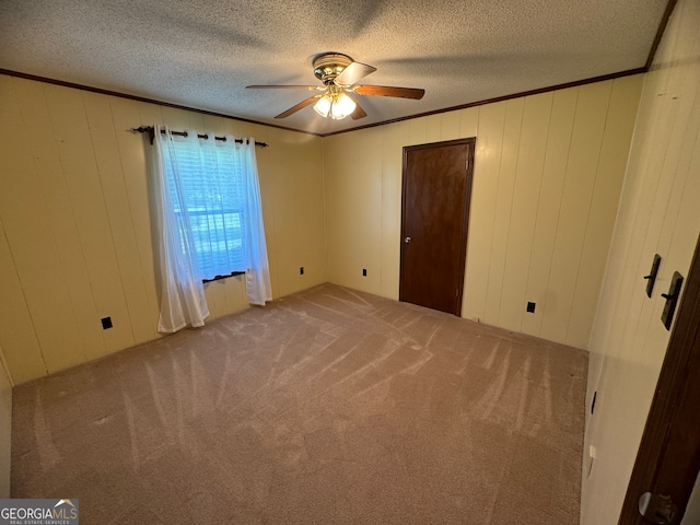 spare room with wooden walls, ceiling fan, carpet flooring, and a textured ceiling