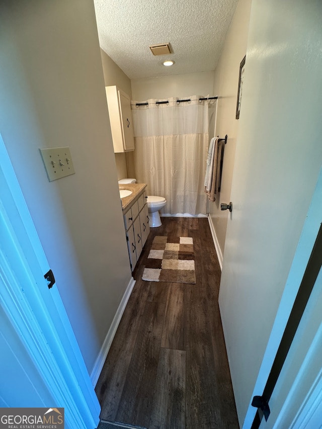 bathroom with vanity, toilet, curtained shower, a textured ceiling, and hardwood / wood-style floors