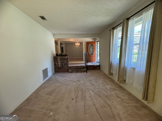 hall featuring a textured ceiling and light carpet