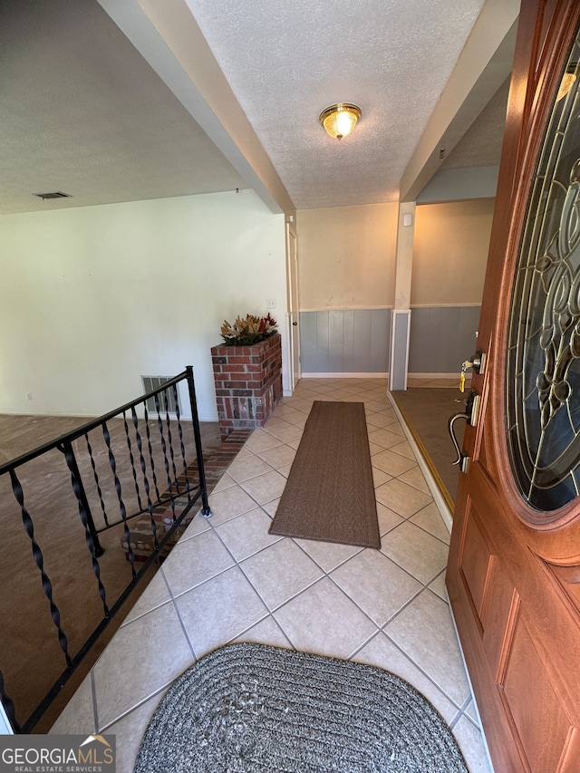 entrance foyer with a textured ceiling and light tile patterned flooring