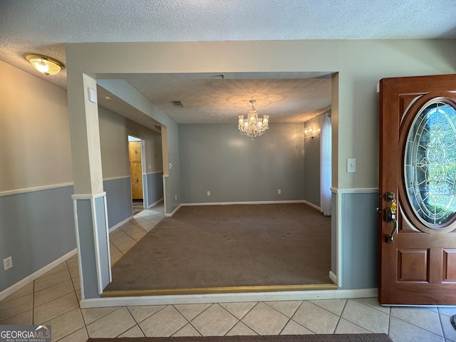 entryway featuring light carpet, a textured ceiling, and a notable chandelier