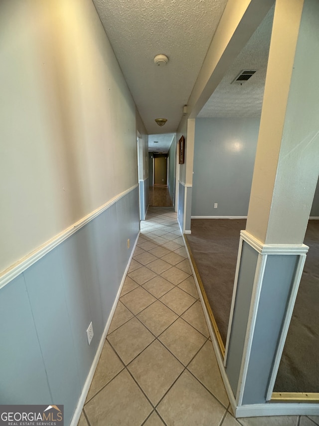 corridor with a textured ceiling and tile patterned floors