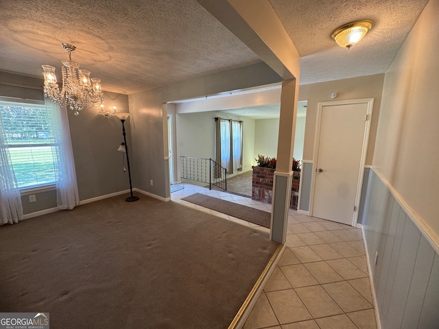 unfurnished room featuring an inviting chandelier, light colored carpet, and a textured ceiling