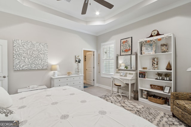 bedroom featuring a ceiling fan, a tray ceiling, wood finished floors, and ornamental molding