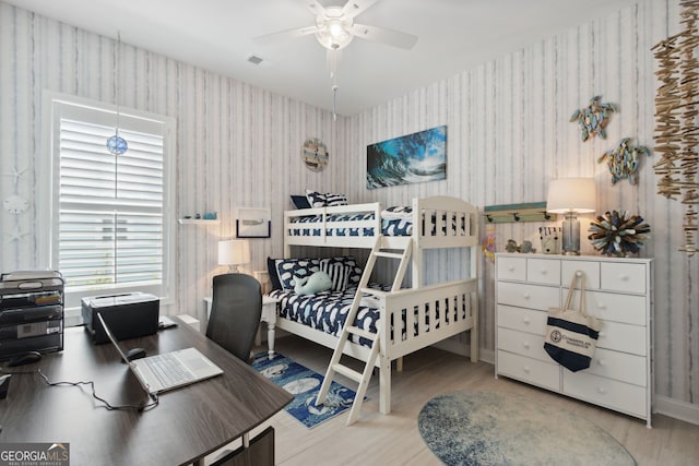 bedroom with wood finished floors and wallpapered walls