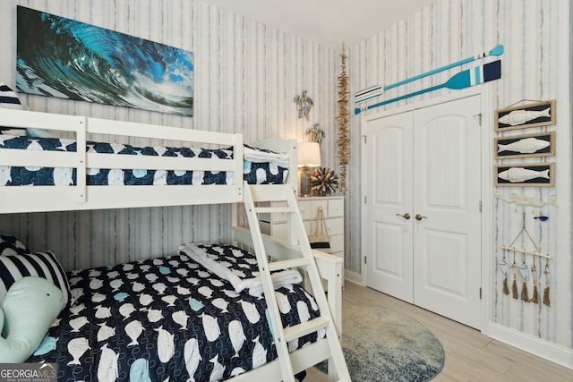 bedroom with wallpapered walls, a closet, and wood finished floors