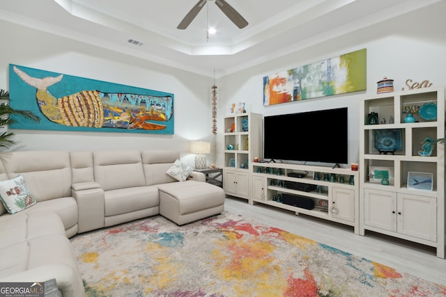 living area featuring crown molding, a raised ceiling, visible vents, a ceiling fan, and wood finished floors