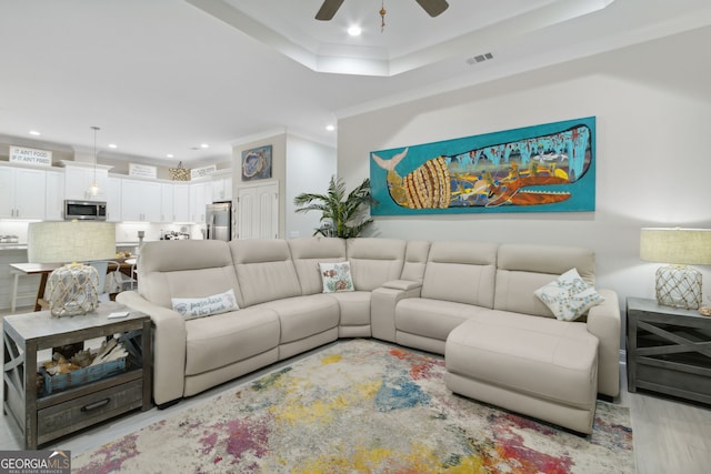 living area featuring a tray ceiling, crown molding, recessed lighting, visible vents, and ceiling fan