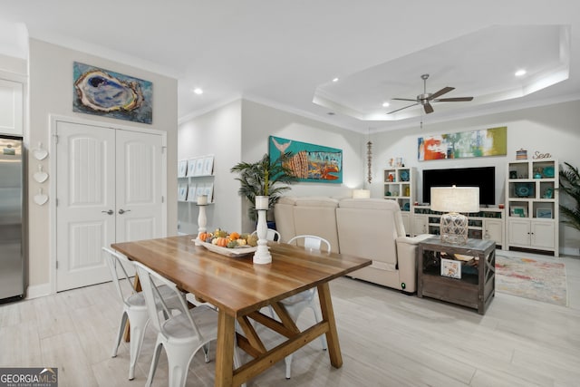 dining area with a tray ceiling, recessed lighting, light wood-style flooring, a ceiling fan, and ornamental molding