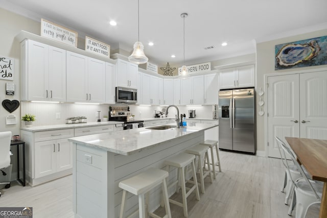 kitchen featuring stainless steel appliances, white cabinetry, a sink, and backsplash