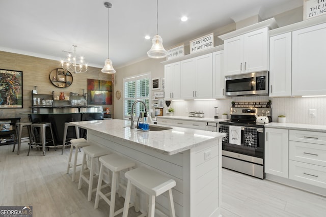 kitchen with stainless steel appliances, tasteful backsplash, ornamental molding, white cabinets, and a sink