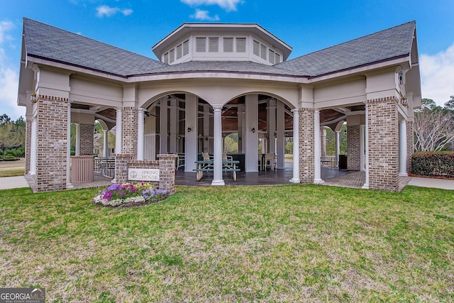 rear view of house featuring a yard, brick siding, and a patio area