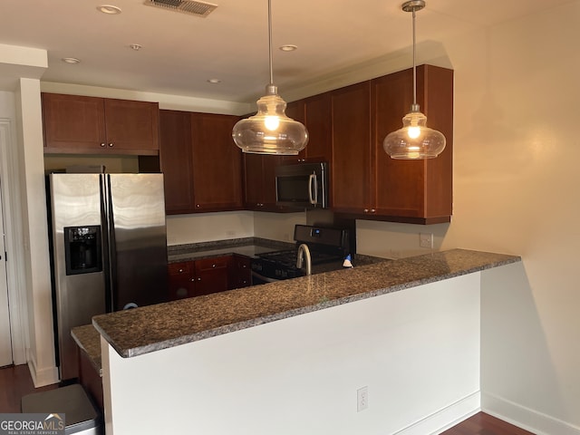 kitchen featuring kitchen peninsula, stainless steel appliances, hanging light fixtures, and dark stone countertops