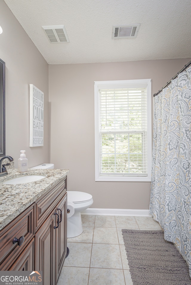 bathroom with tile patterned flooring, a textured ceiling, vanity, and toilet