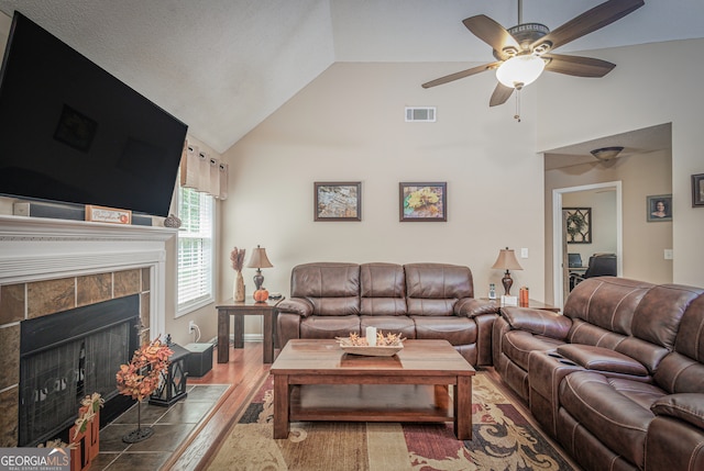 living room featuring wood-type flooring, a fireplace, ceiling fan, and high vaulted ceiling