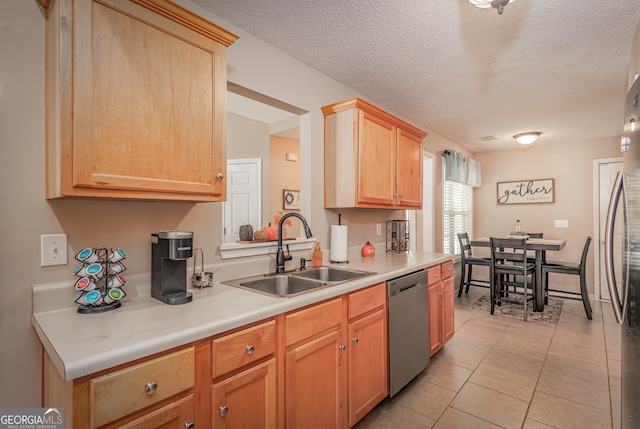 kitchen with light brown cabinets, dishwasher, light tile patterned floors, a textured ceiling, and sink