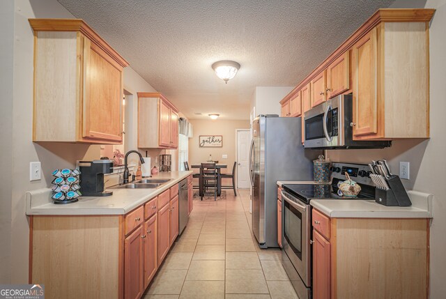 kitchen featuring a textured ceiling, light tile patterned flooring, sink, light brown cabinets, and appliances with stainless steel finishes