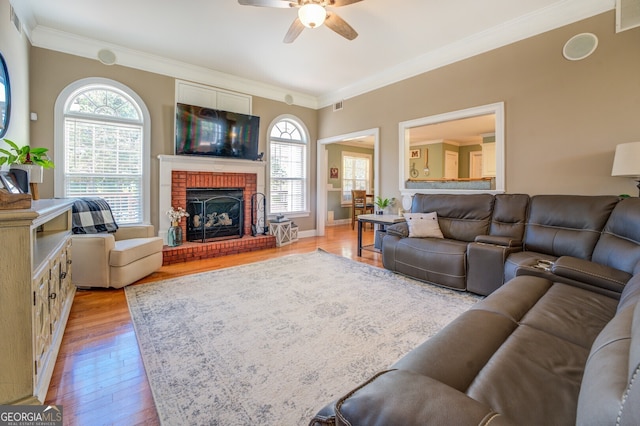 living room featuring a fireplace, ceiling fan, light hardwood / wood-style flooring, and a wealth of natural light