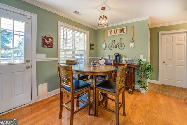 dining room featuring light hardwood / wood-style floors, ornamental molding, and plenty of natural light