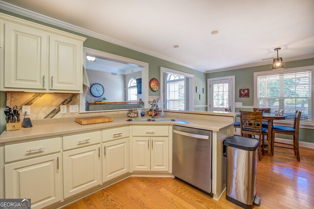 kitchen with light wood-type flooring, sink, kitchen peninsula, hanging light fixtures, and stainless steel dishwasher